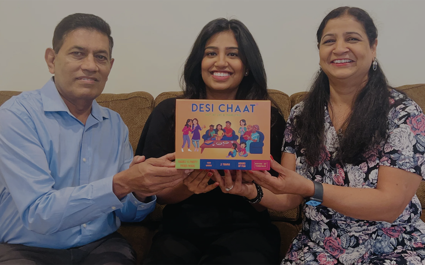 Three family members sitting together on a sofa holding the Desi Chaat box
