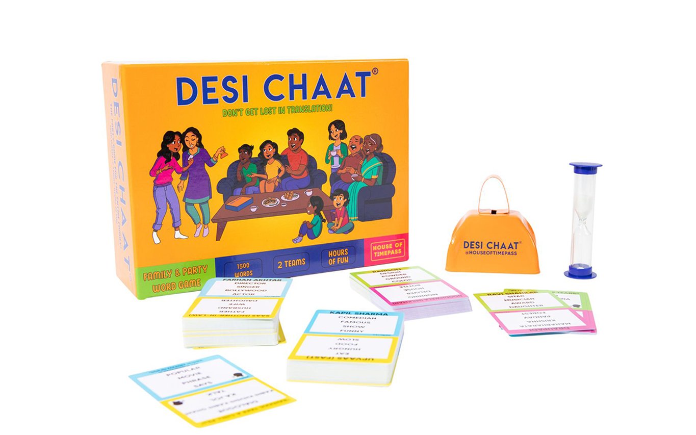 Desi Chaat game box with colourful word cards, the cowbell and sand timer laid out beside it